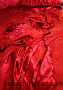 A bed with red satin sheets